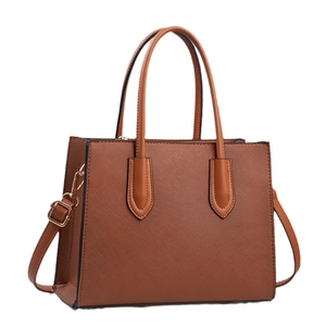 Bolso tote de cuero Saffiano marrón con herrajes dorados y correa ajustable sobre blanco
