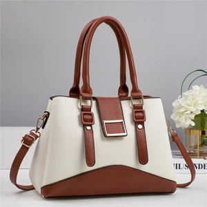 Detail of structured cream and brown leather handbag with gold metal clasp and double handles
