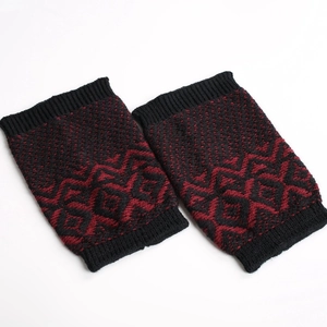 Detailed view of knitted leg warmers with black and red geometric jacquard pattern