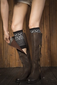 Close-up of knit leg warmers with black and white geometric patterns over leather boots