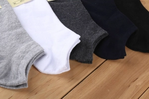 Dettaglio di cinque paia di calzini bassi in cotone in colori neutri su sfondo legno