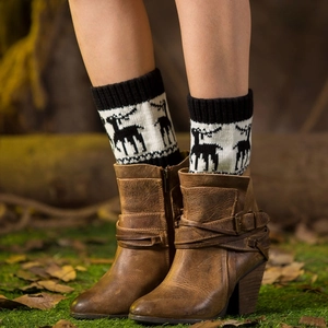 Winter knitted leg warmers with black and white reindeer pattern paired with brown boots