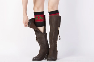 Detail view of knitted Christmas leg warmers with reindeer patterns and winter boot cuff
