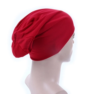 Side view of a soft red knitted slouchy beanie hat worn by a model on white background