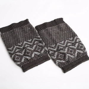 Detailed view of thick knitted leg warmers with grey geometric jacquard wave patterns