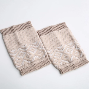 Close-up of beige knit leg warmers featuring Nordic geometric patterns and ribbed cuffs