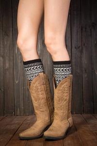 Détail de jambières en tricot bohème assorties à des bottes de cow-boy marron vintage