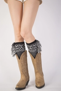 Detail of bohemian knit leg warmers with black and white tassels on brown boots