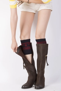 Close-up of knit leg warmers with red reindeer pattern worn over brown leather boots