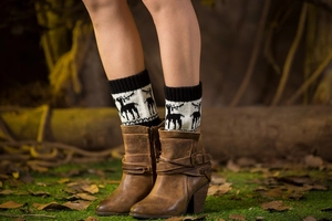 Close-up of knit leg warmers with reindeer pattern and brown vintage leather ankle boots