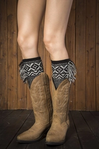 Detail of bohemian knit leg warmers with geometric patterns and tassels over leather boots