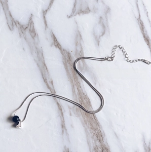 Close-up of S925 sterling silver chain with black onyx bead and triangle pendant