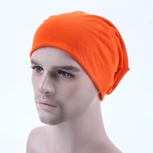 Detail view of vibrant orange knitted slouchy beanie on male mannequin head for casual style