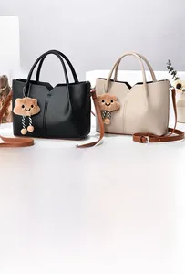 Detail of color-block tote bags in black and beige PU leather with cloud plush charms