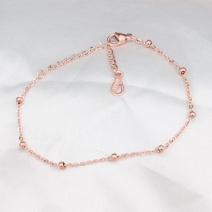 Macro view of rose gold thin bead bracelet with 18KGP engraving on the clasp tag