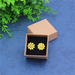 Macro shot of yellow daisy flower earrings placed in a vintage kraft jewelry box