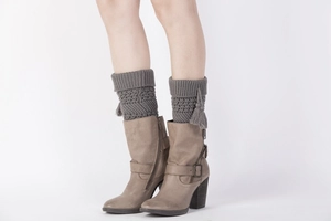 Detail of dark grey knit leg warmers with cable pattern and side tassels on boots