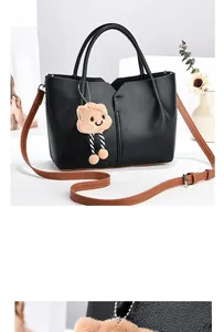 Detail of black tote bag with brown straps and cute plush cloud pendant accessory