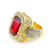 Macro detail of gold-plated hip hop ring with large red gemstone and pavé crystal setting