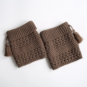 Detailed close-up of brown knit leg warmers featuring hollow patterns and fringe tassels