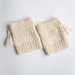 Detail of cream cable-knit leg warmers with hollow patterns and side tassels