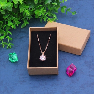 Rose gold necklace with six-prong zircon pendant inside a kraft paper jewelry box