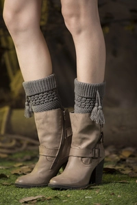 Detail of grey knitted leg warmers with hollow patterns and side tassel accents