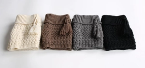 Detail of four-color knit leg warmers with textured wave patterns and side fringe tassels