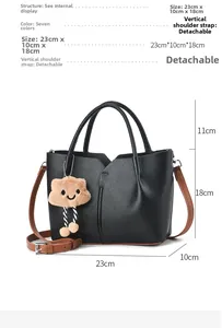 Detail view of black pebble leather tote with brown strap and plush cloud charm