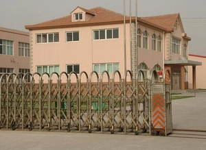 Outdoor view of an industrial stainless steel electric retractable gate with diamond mesh