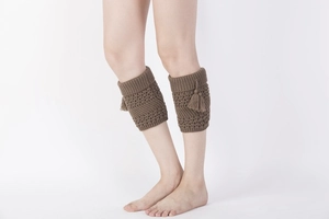 Close-up of dark brown knit leg warmers with textured patterns and fringe detailing