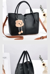 Detail of black litchi pattern bucket bag with V-shaped opening and plush charm