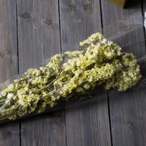 Dried yellow statice flower bouquet for DIY floral arrangements on wood background