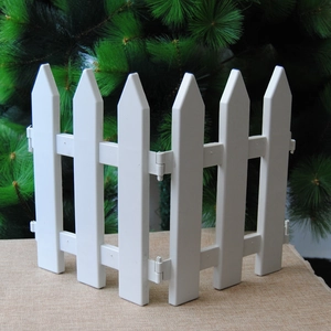 Close-up of a white plastic fence for Christmas tree decoration with green pine background