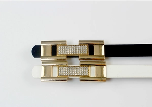 Détail macro de ceintures fines avec boucles rectangulaires dorées et strass brillants