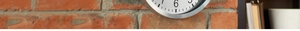 Detail of 12-inch stainless steel clock on red brick wall with industrial decor