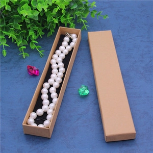 Macro view of long kraft paper necklace box with black velvet lining on blue background