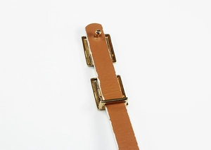 Détail d'une ceinture en similicuir marron avec boucle et rivet en alliage doré poli