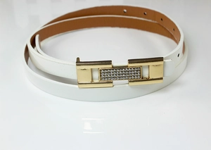 Détail d'une ceinture blanche pour femme avec boucle dorée ornée de strass