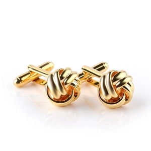 Detailed view of polished gold twisted knot cufflinks with reflection on white background