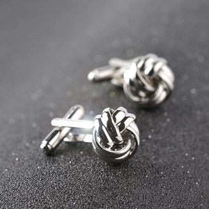 Polished silver twisted knot cufflinks for men's dress shirts on a textured grey background