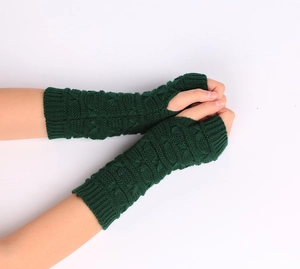 Detailed knit texture of dark green fingerless arm warmers with classic cable pattern