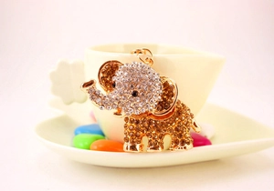 Close-up of diamond-studded metal elephant keychain on white dish with aesthetic decor