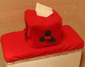 Detailed view of red Christmas toilet tank cover and tissue box with holly leaf accents