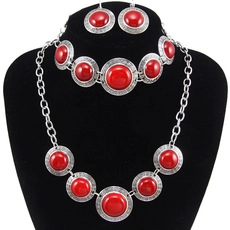 Detail of vintage silver necklace set featuring red circular stones on a velvet display