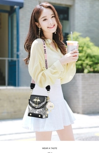 Detail of crossbody bag featuring paisley pattern, golden swan clasp and pink logo strap