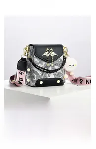 Detail of crossbody bag featuring paisley pattern, flamingo pearl clasp and wide strap