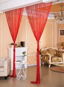 Close-up of red fringe curtain with silver glitter strings in an elegant home interior