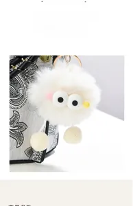 Detail of cartoon eye plush charm with gold metal hook on a shoulder handbag strap