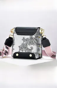 Detail view of paisley print crossbody bag with gold hexagonal rivets and pink strap